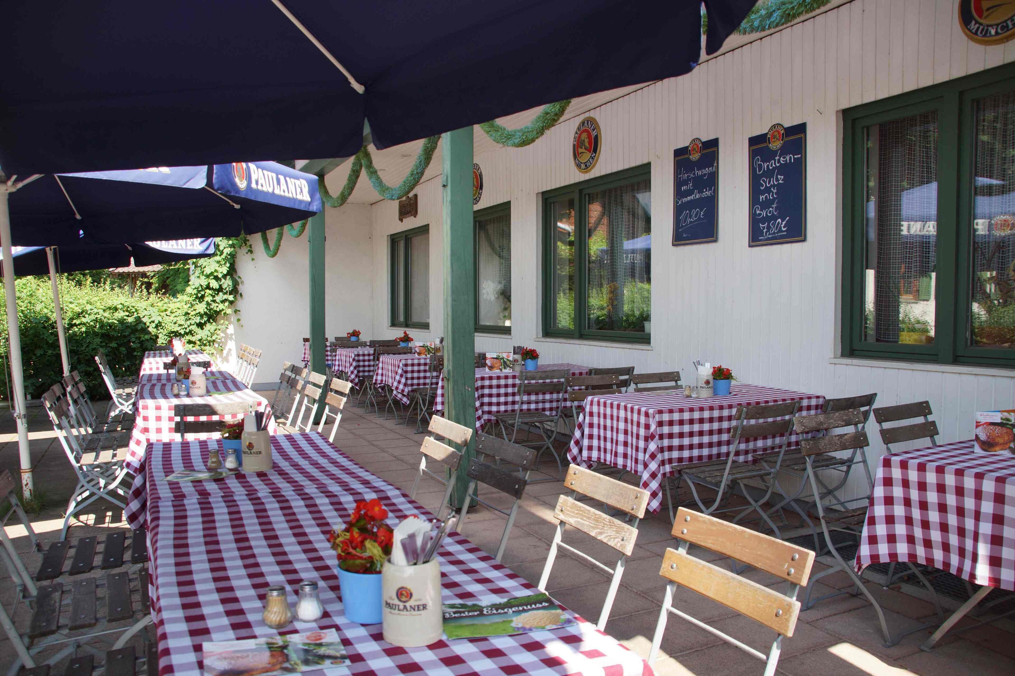 Een terras met gehaakte tafelkleden, houten stoelen en parasols.