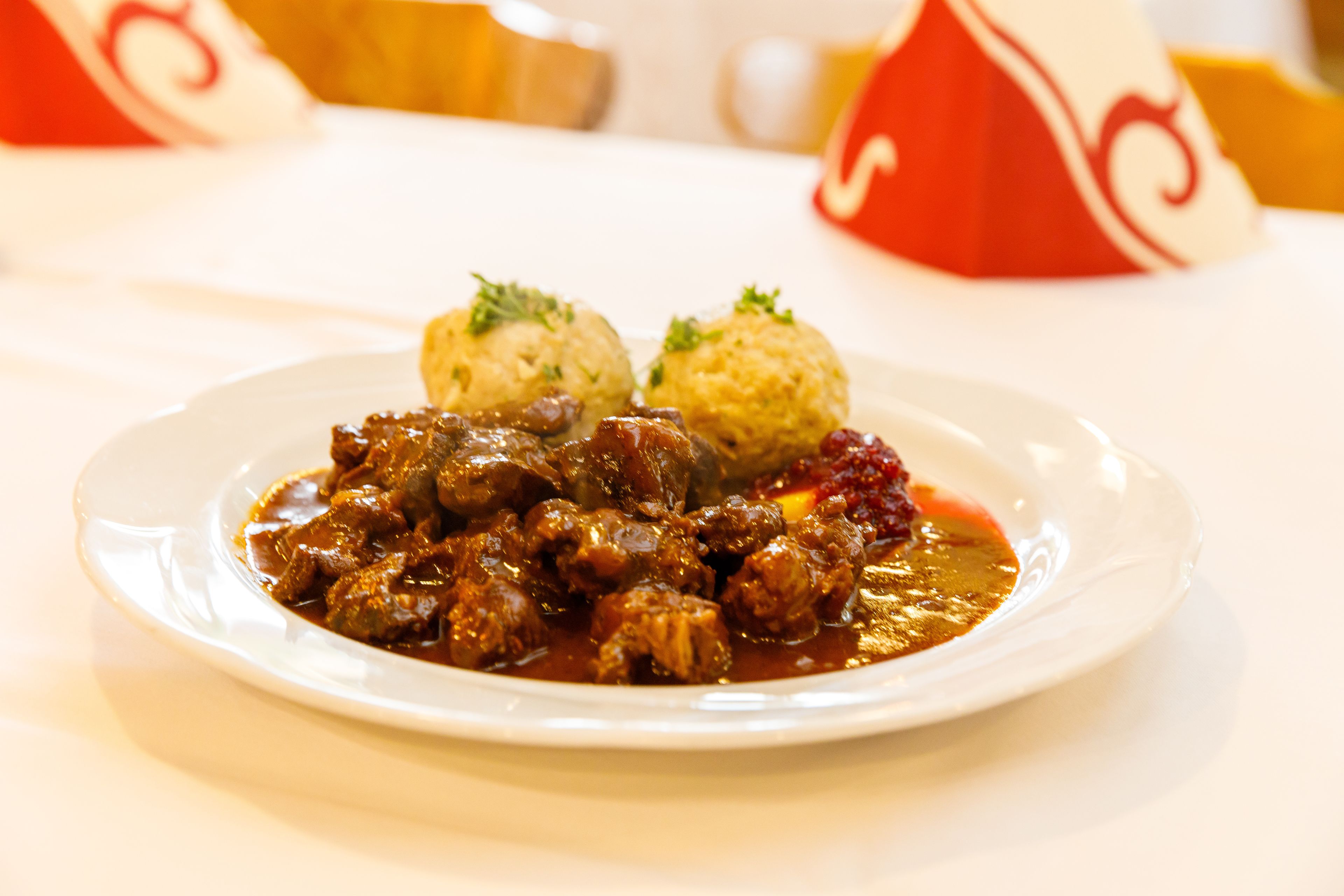 A plate of food with meat and dumplings on a white plate.