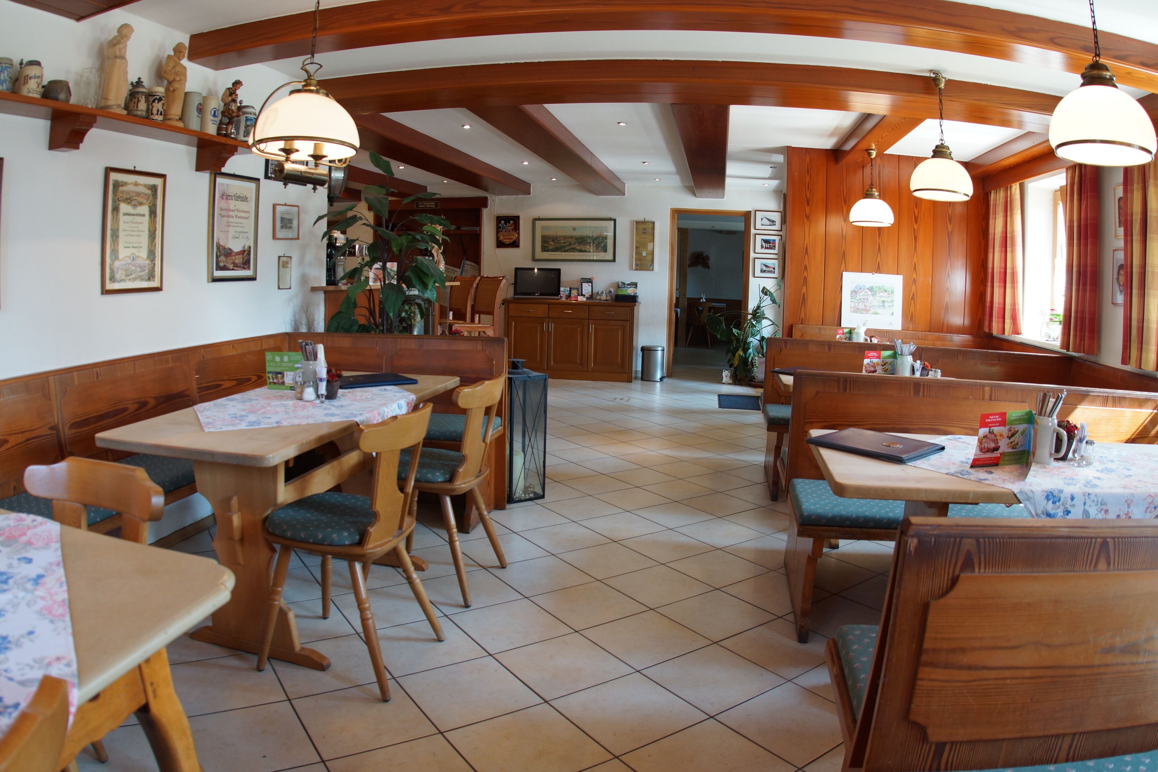 Un restaurante con mobiliario de madera, suelo de baldosas e iluminación colgante.