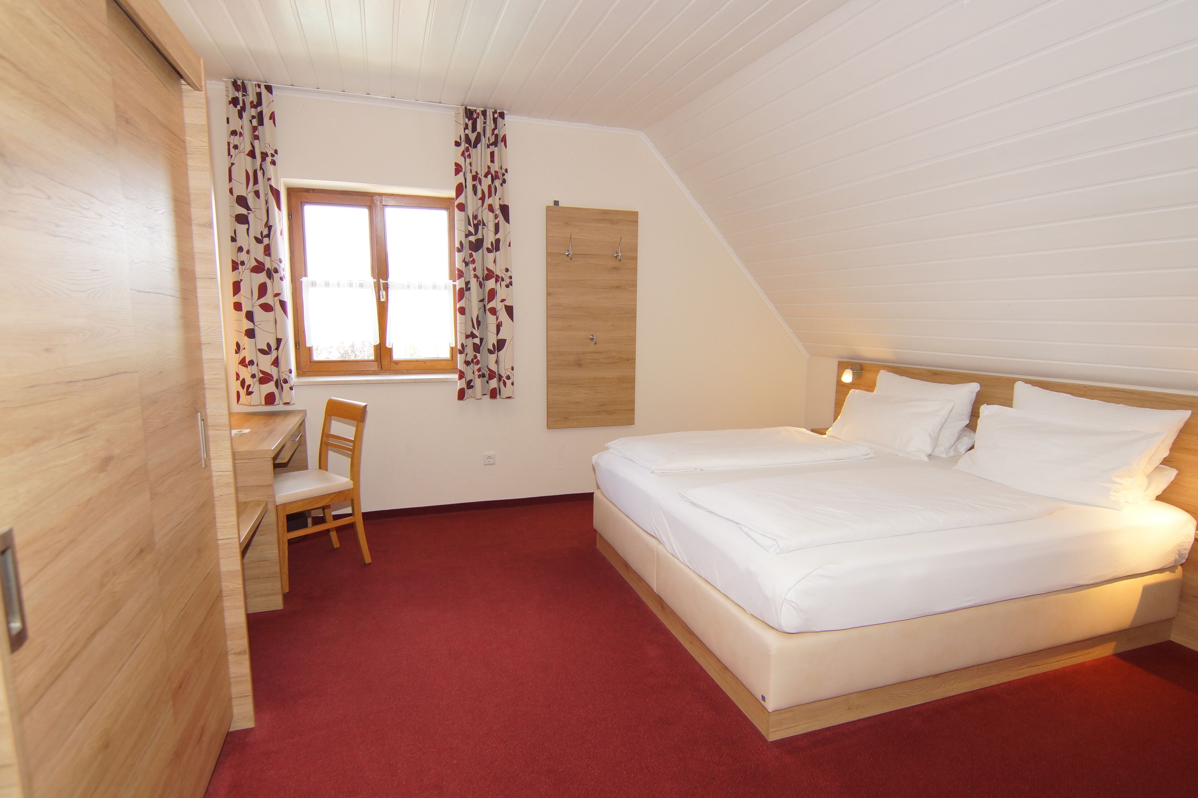 A bedroom with a bed, a desk, and a chair.