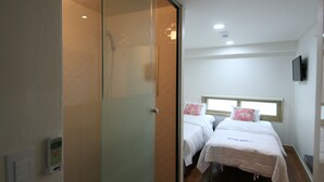 A hotel room with a sliding door leading to a shower area, two beds with pillows, and a pair of slippers on the floor. - Star Guest House (Seoul)