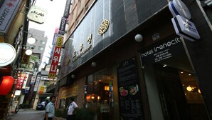 A hotel with a modern facade, signage for a restaurant, and a visible entrance. - Star Guest House (Seoul)