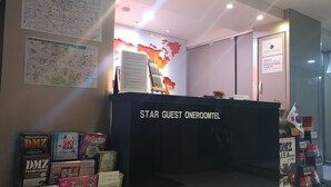 A hotel reception area with a Star Guest Oneroom sign, a map, and various travel brochures. - Star Guest House (Seoul)