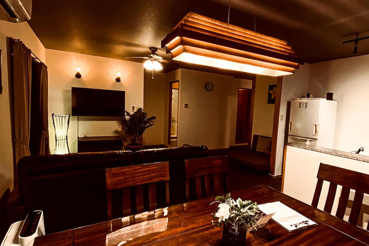 A dining area with a wooden table, chairs, a vase with flowers, and a ceiling fan.