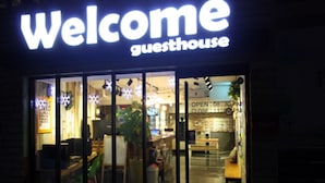 A guesthouse with a 'Welcome' sign, glass doors, and a visible interior including a reception area and seating. - Welcome Guesthouse Myeongdong (Seoul)