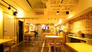 A restaurant with a brick wall, wooden tables, and chairs. - Welcome Guesthouse Myeongdong (Seoul)