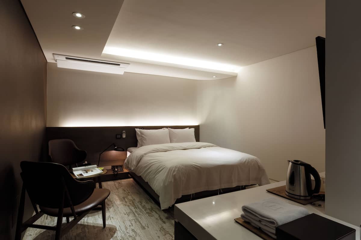 Ein modernes Hotelzimmer mit einem Bett, einem Schreibtisch, einem Stuhl und einer Kaffeemaschine.