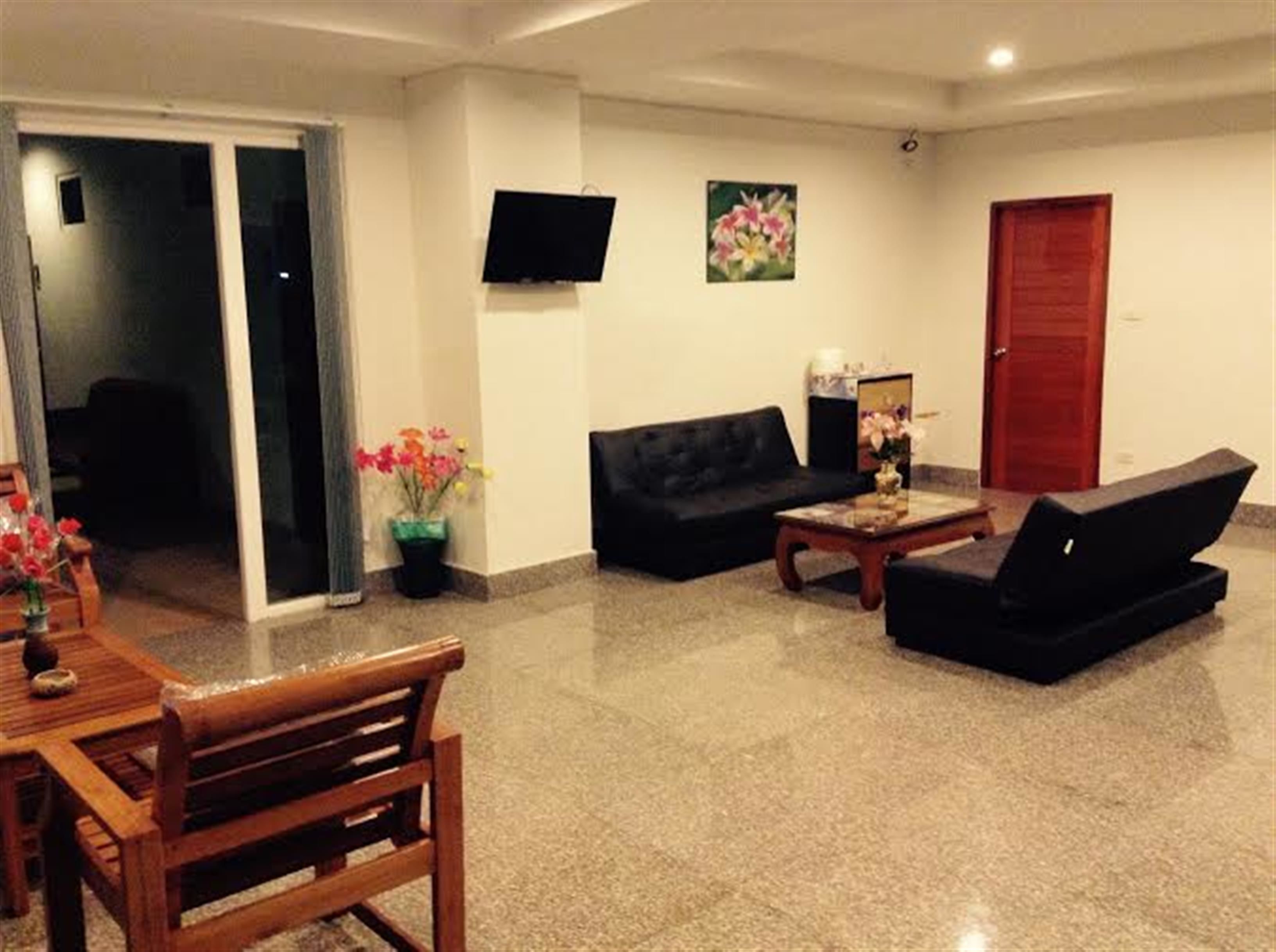Una sala de estar con un sofá, una mesa de centro, un televisor montado en la pared y una puerta.