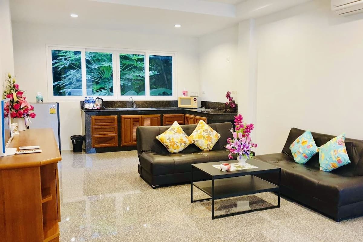 Una sala de estar moderna con un conjunto de sofás, una mesa de centro y una cocina al fondo.