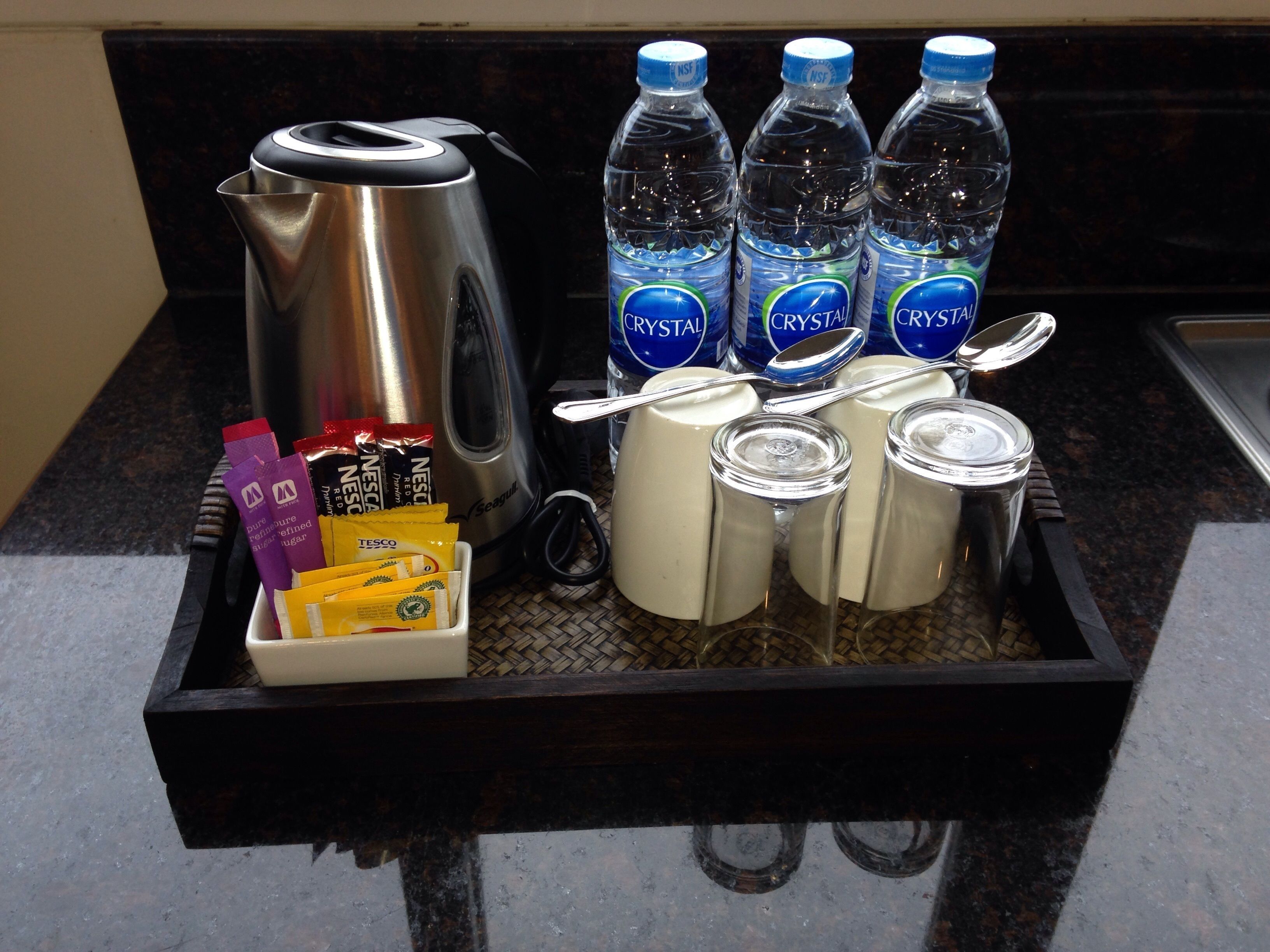 A tray with a coffee maker, bottled water, coffee packets, and milk cartons.