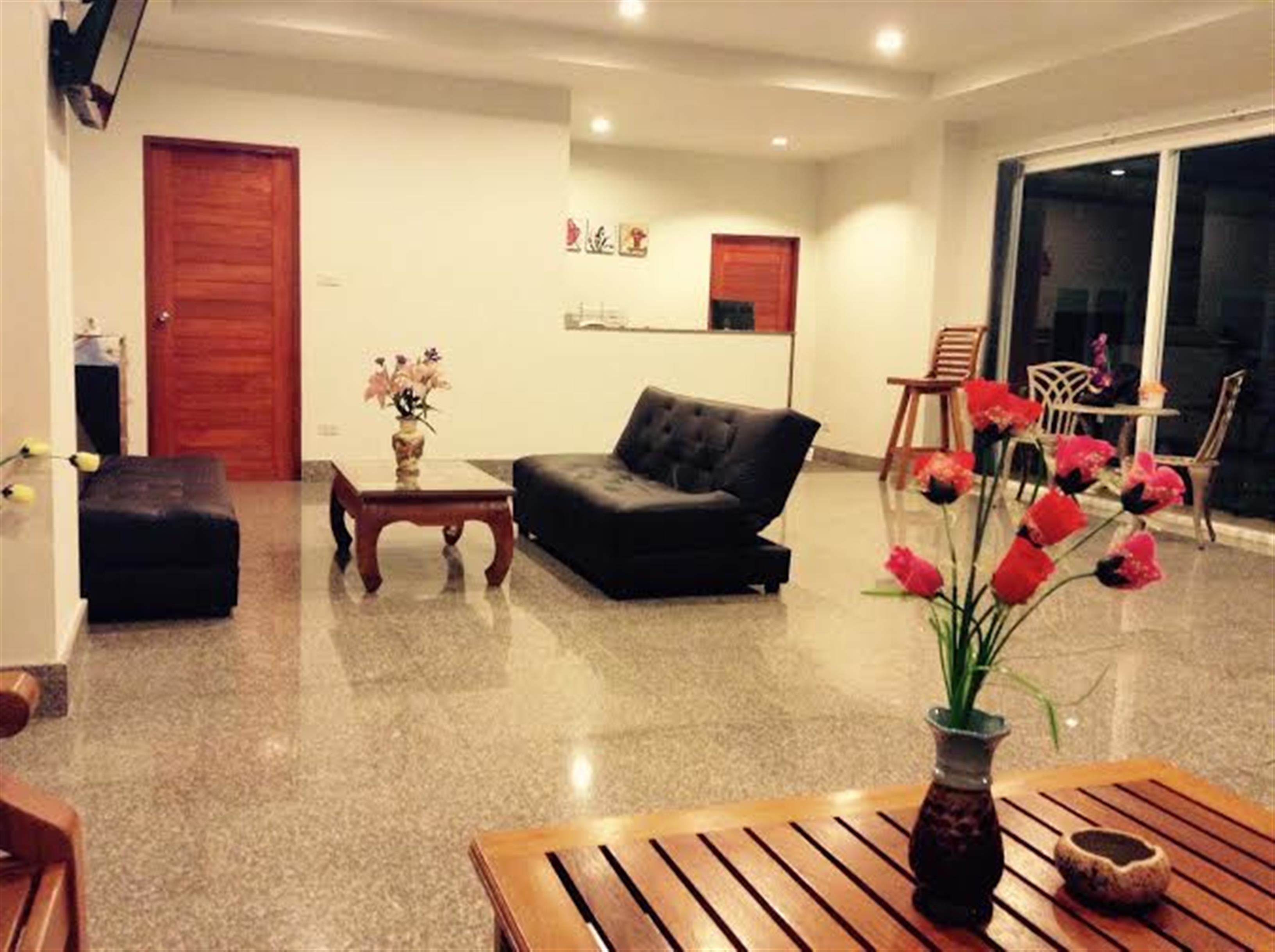 A living room with a black sofa, a wooden coffee table, and a vase with flowers.