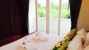 Una habitación de hotel con cama, ventana con vistas a zonas verdes y balcón.