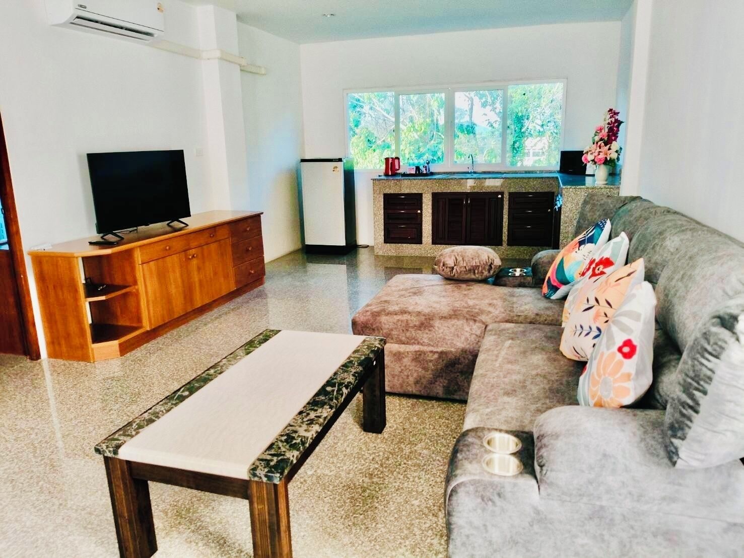 Un salon avec un téléviseur, un meuble en bois, un canapé et une petite table.