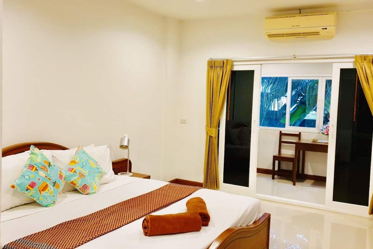 Habitación de hotel con cama, escritorio y vista a través de puertas de cristal.
