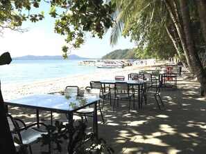 A beachside restaurant with tables and chairs, overlooking the sea and boats. - Siray House (Ratsada)