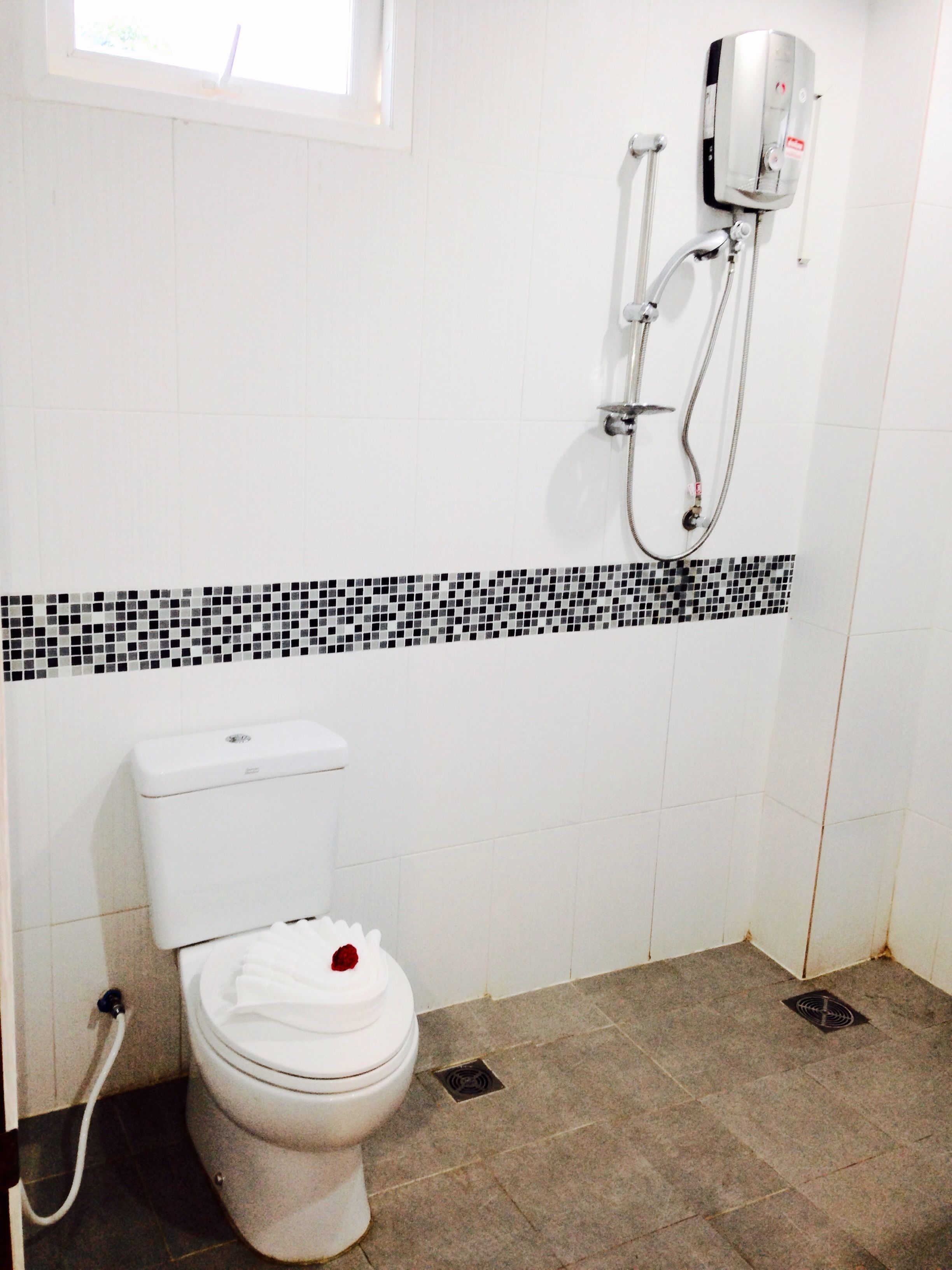 A bathroom with a toilet, a shower, and a tiled floor.