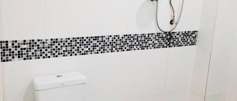 A bathroom with a toilet, a shower, and a tiled floor.