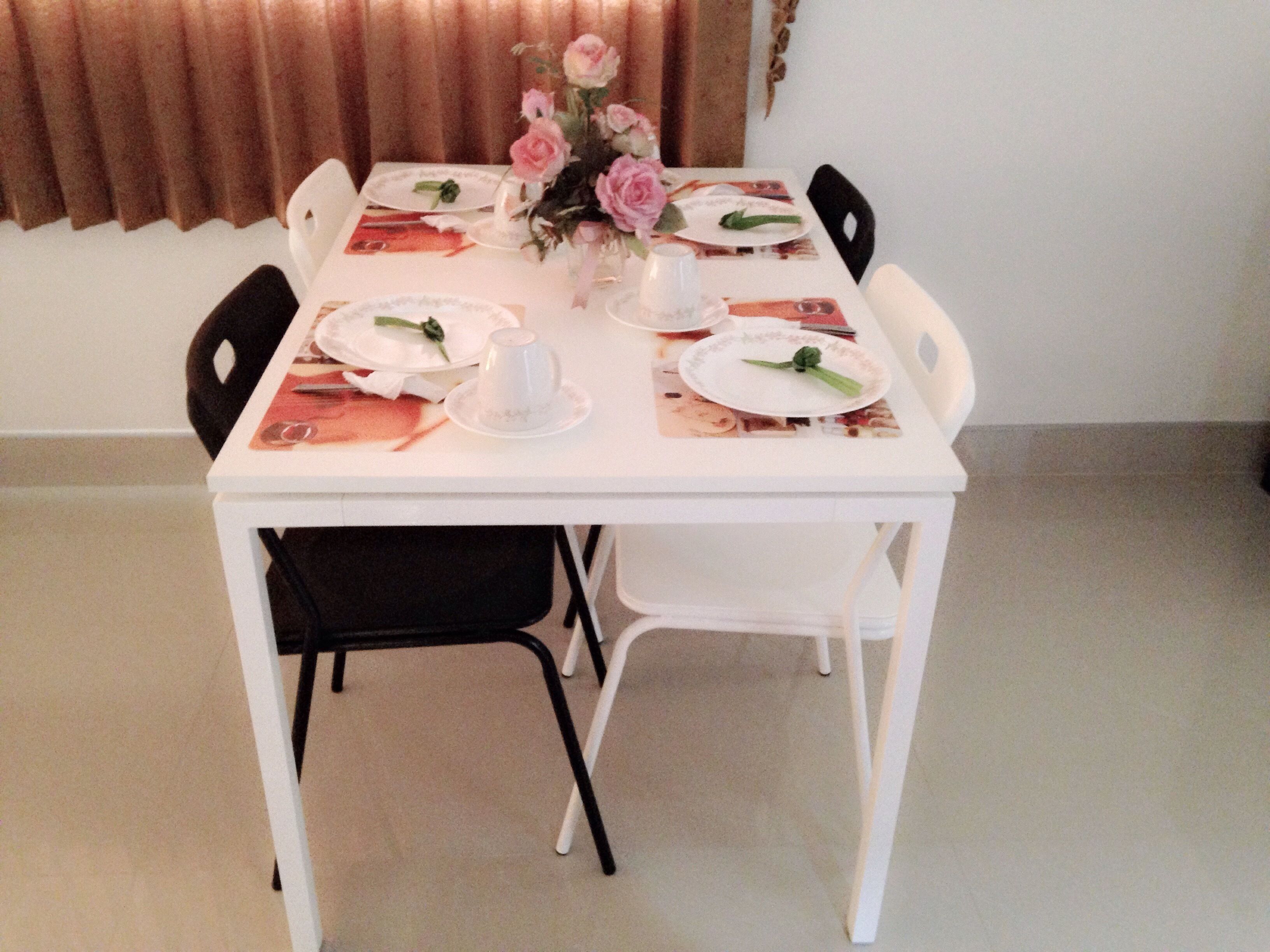 A dining table set with plates, a vase of flowers, and a cup.