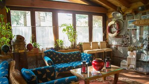 A cozy living room with blue patterned sofas, a glass coffee table, and a variety of decorative items including a life preserver, a red lantern, and a wicker chair. - Hotel Ristorante La Perla (Varallo Pombia)