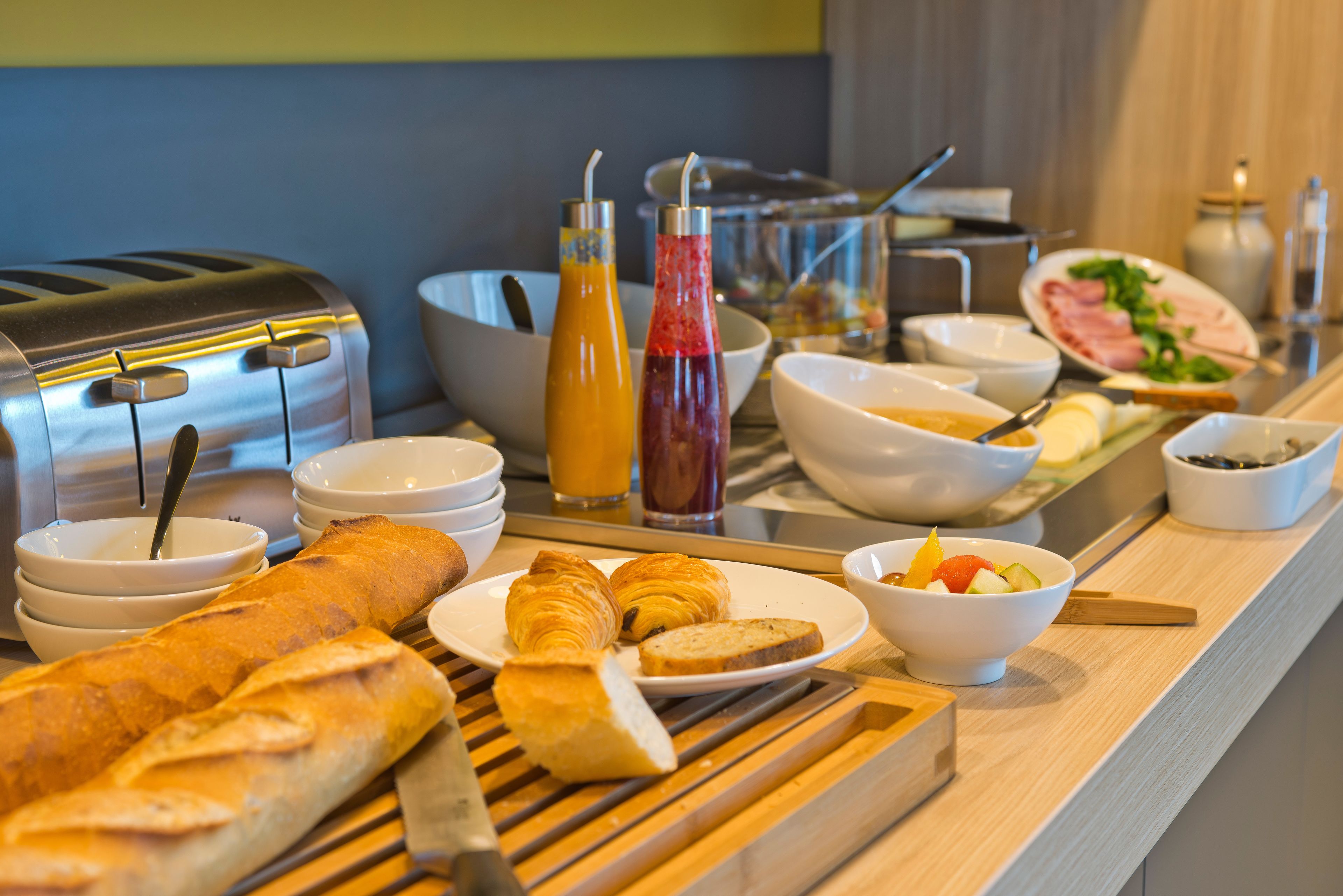 Un buffet de petit-déjeuner comprenant du pain, des croissants, des fruits et divers accompagnements.