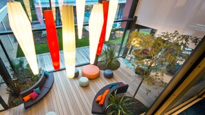 Un espacio exterior moderno con asientos redondos y curvos, una terraza de madera y lámparas colgantes.