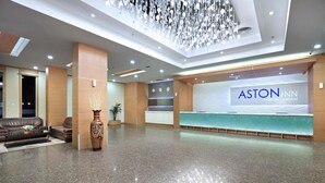 A spacious lobby with a reception desk labeled "ASTON INN," a large vase, and a modern chandelier. - Aston Inn Gideon Batam (Batam)