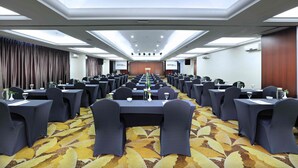 A conference room with a long table, rows of chairs, and a patterned carpet. - Aston Inn Gideon Batam (Batam)