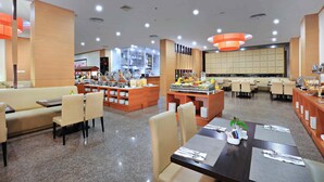 A modern hotel dining area with a buffet, seating arrangements, and a kitchen in the background. - Aston Inn Gideon Batam (Batam)
