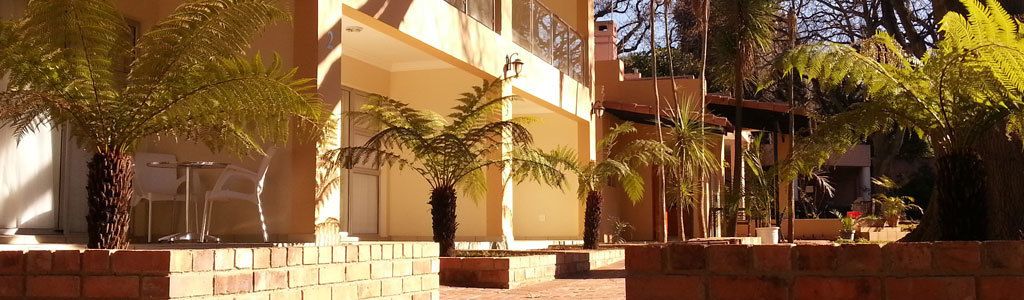 Un immeuble doté de nombreux balcons, de plantes en pot et d’un chemin bordé de briques.