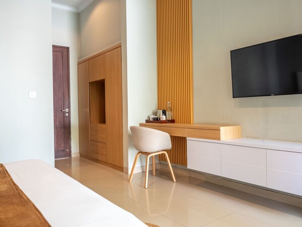 Una habitación moderna con un armario de madera, un banco blanco, un escritorio de madera con una silla y un televisor de pantalla plana montado en la pared.