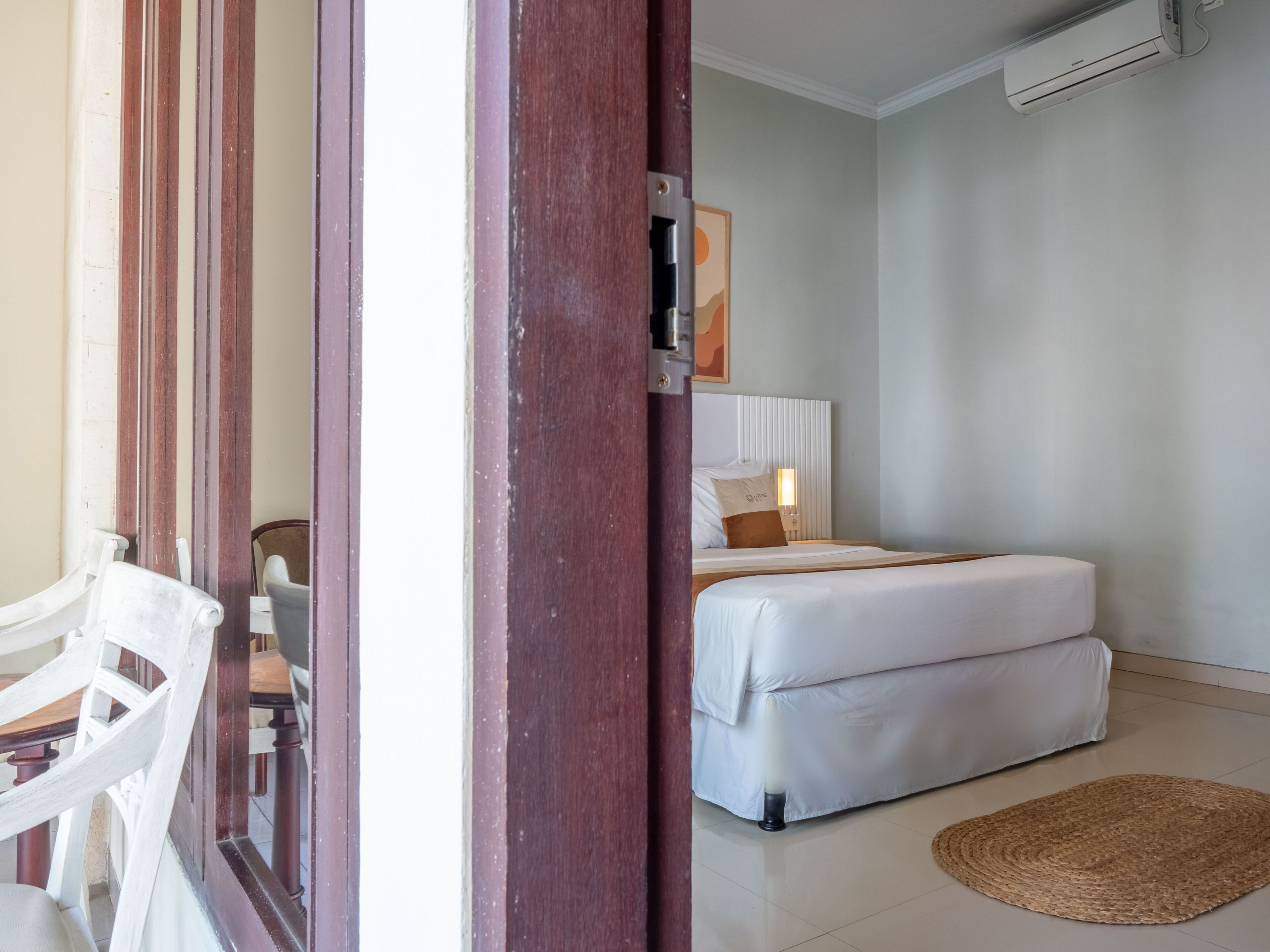 A hotel room with a bed, bedside table, and a wall-mounted air conditioner.