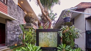 Zona de recepción con pared de piedra, mostrador de recepción y señalización que indica el camino a la habitación.