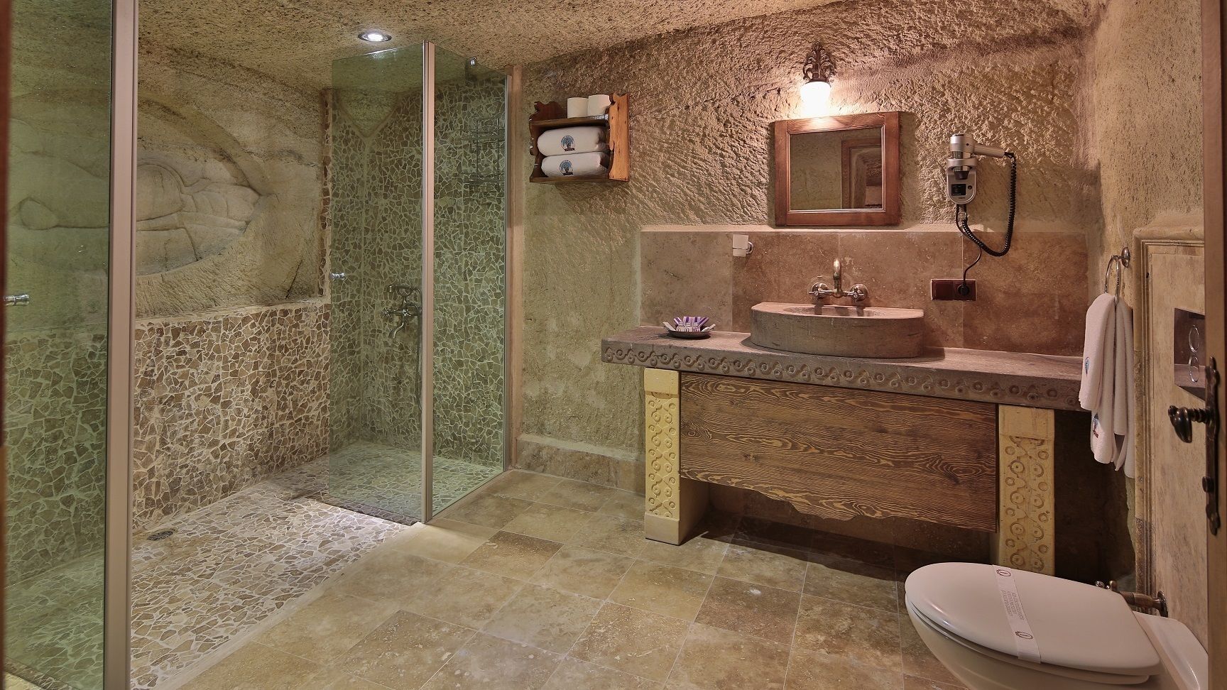 A bathroom with a glass-enclosed shower, a sink with a mirror, and a toilet.