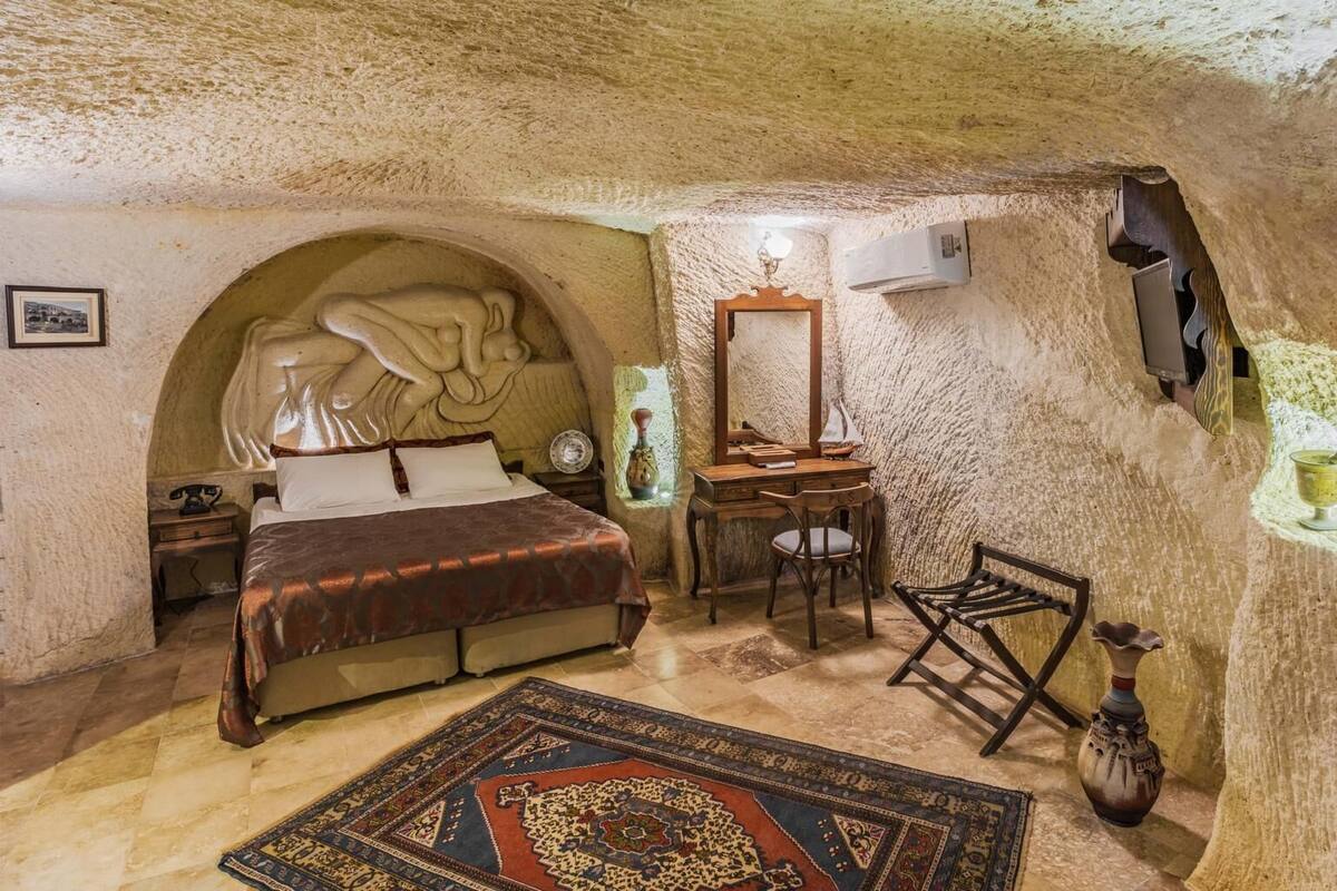 Una habitación acogedora con cama, escritorio y silla, que destaca por un techo y paredes de aspecto similar a una cueva.