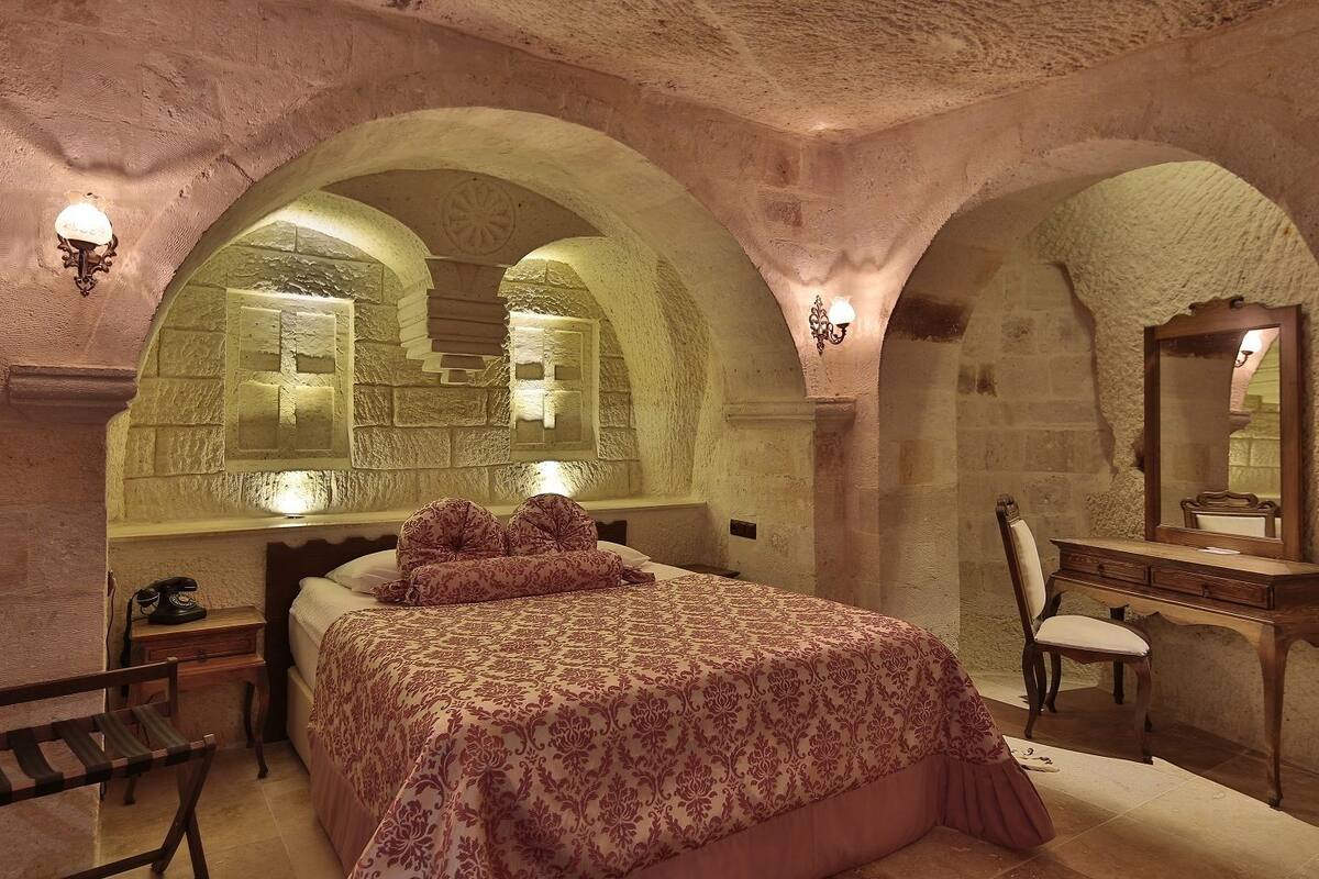 Un dormitorio con cama, cómoda de madera, silla y teléfono.