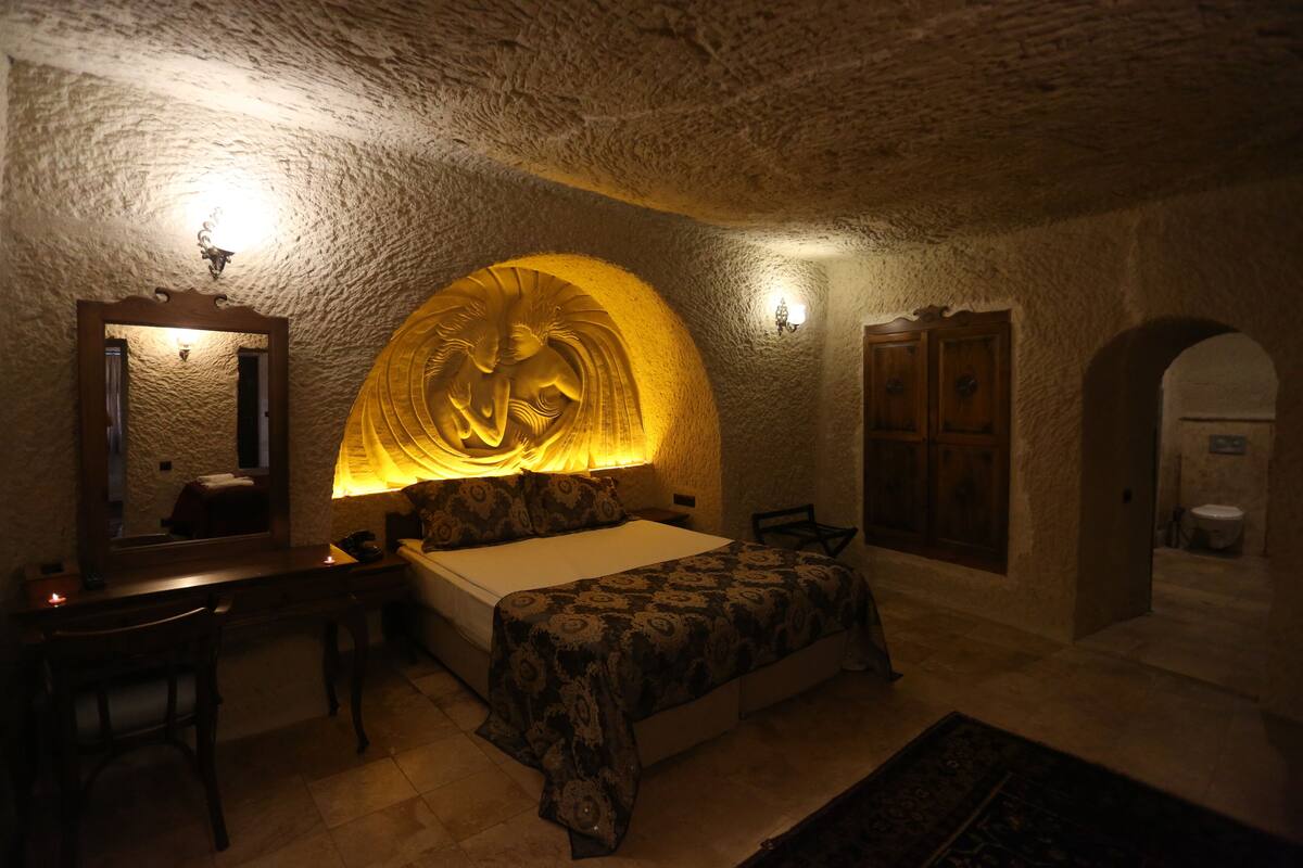 Una habitación con cama, escritorio y una amplia escultura en la pared.