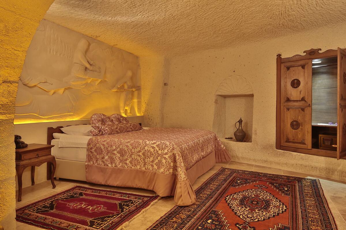Un dormitorio con cama, mesita de noche, cómoda, espejo y estante en la pared.