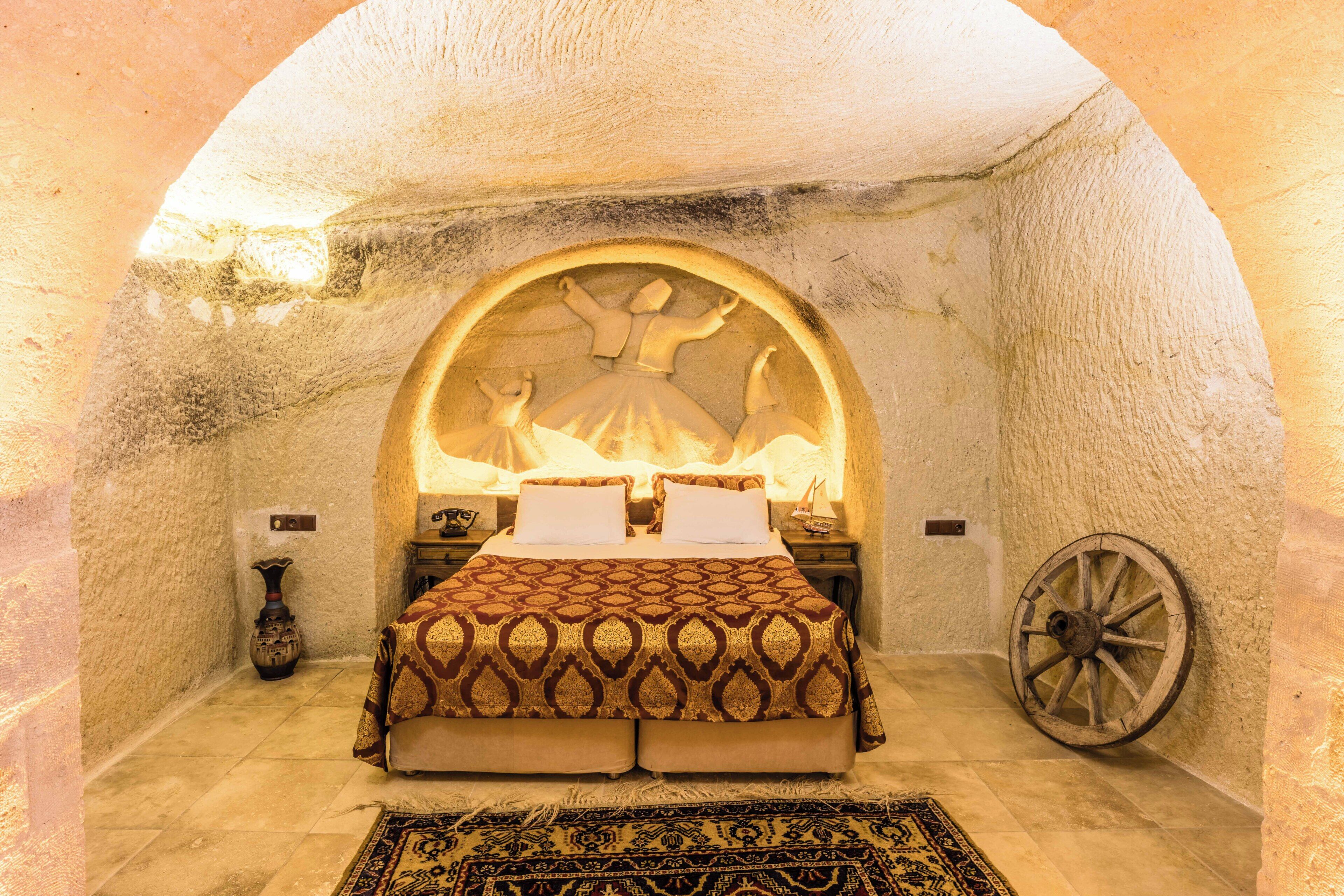 A cozy bedroom with a large bed, a decorative rug, and a unique stone archway.