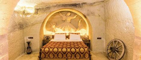 A cozy bedroom with a large bed, a decorative rug, and a unique stone archway.