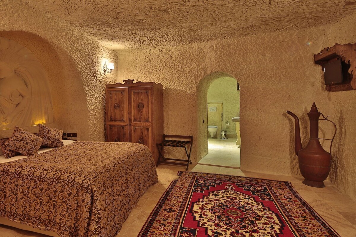 A bedroom with a bed, a wooden wardrobe, a rug, and a wall with a carved design.