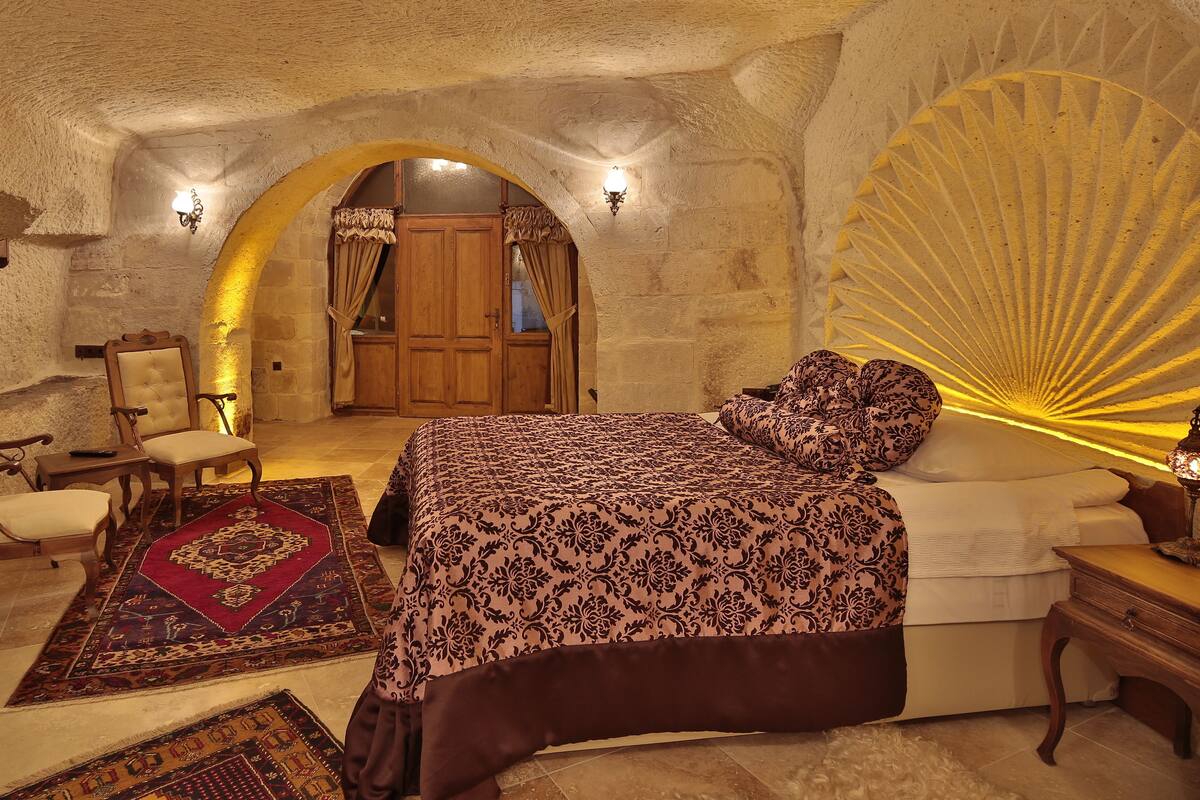 Un dormitorio con una cama grande, una silla de madera, un sofá y un abanico decorativo.