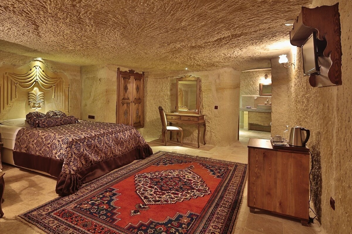 A bedroom with a bed, a chair, a desk, a mirror, and a rug.