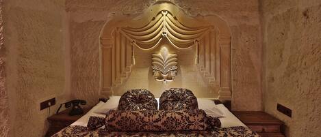 A bedroom with a large bed, a decorative headboard, and a nightstand with a telephone.