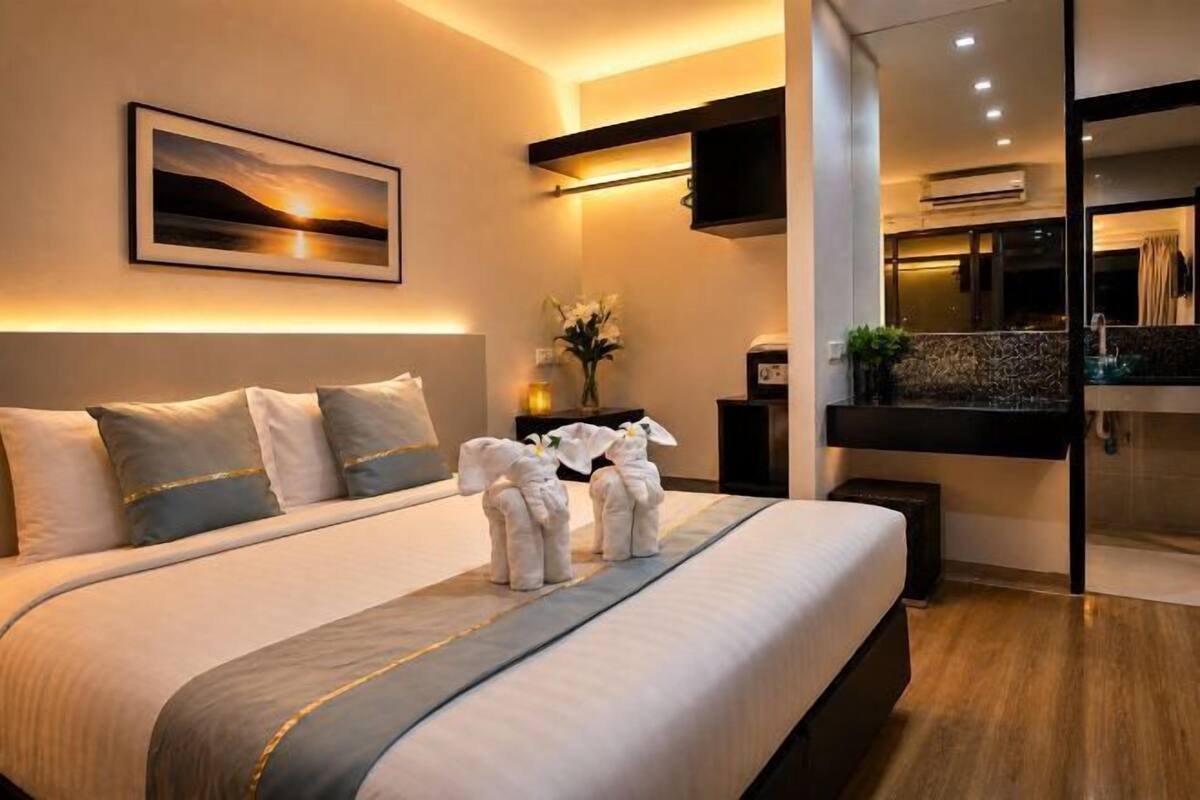 A modern hotel room with a large bed, a mounted TV, and a view of the pool area.
