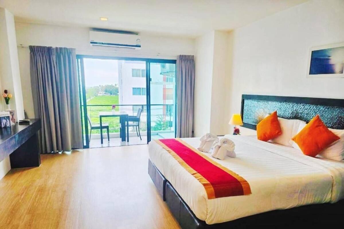 A hotel room with a large bed, a desk, and a balcony with a view.