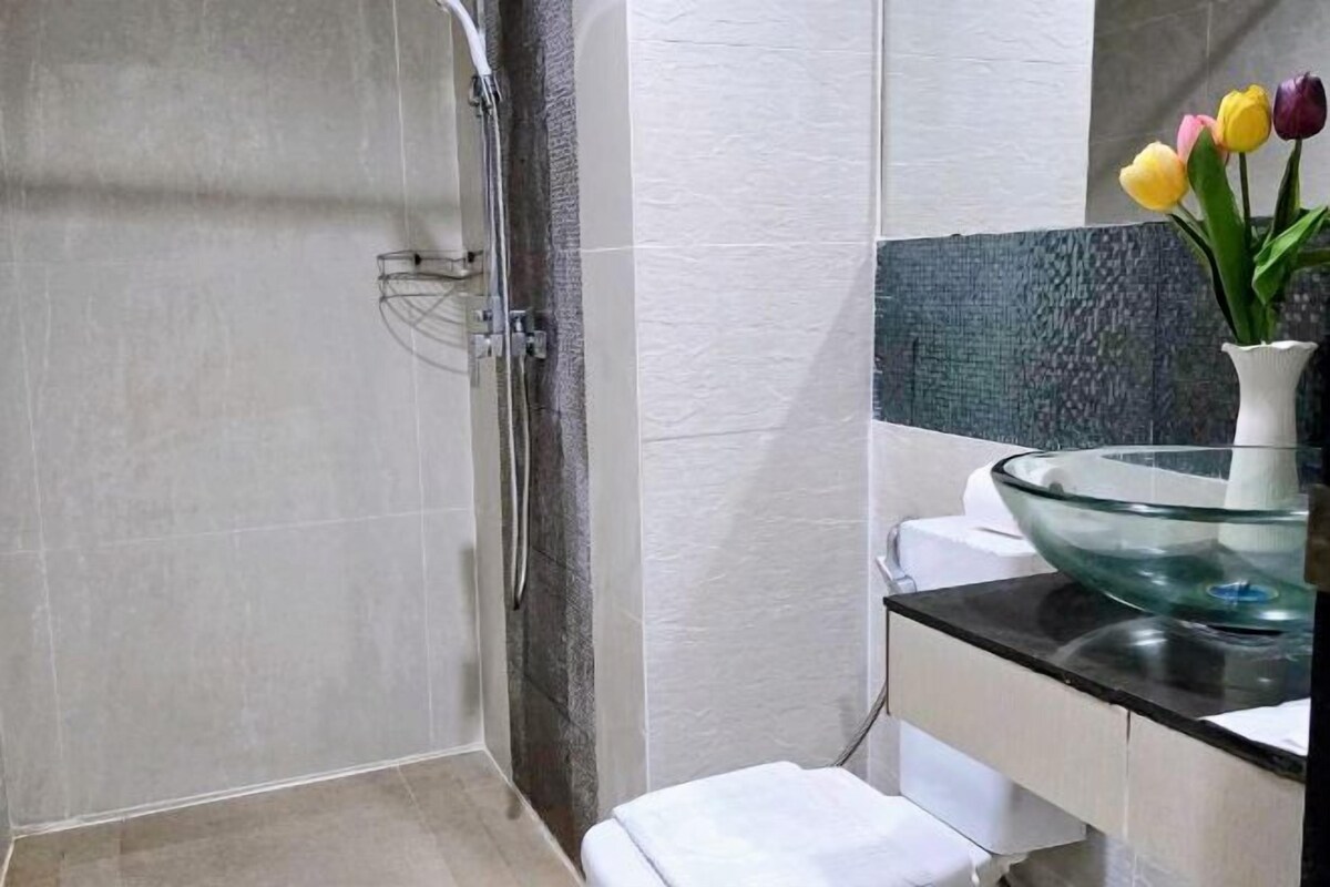 A bathroom with a glass bowl sink, a shower, and a toilet.