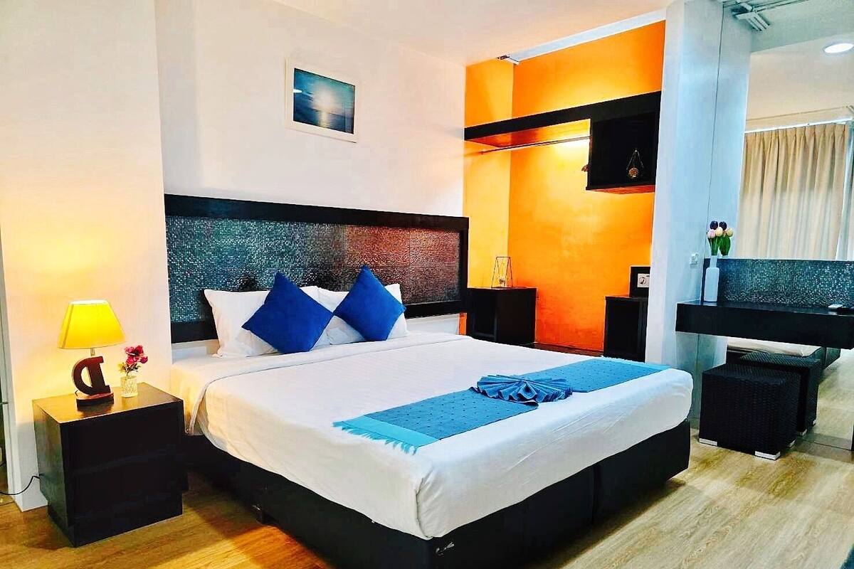 A modern hotel room with a large bed, a TV, and a desk.