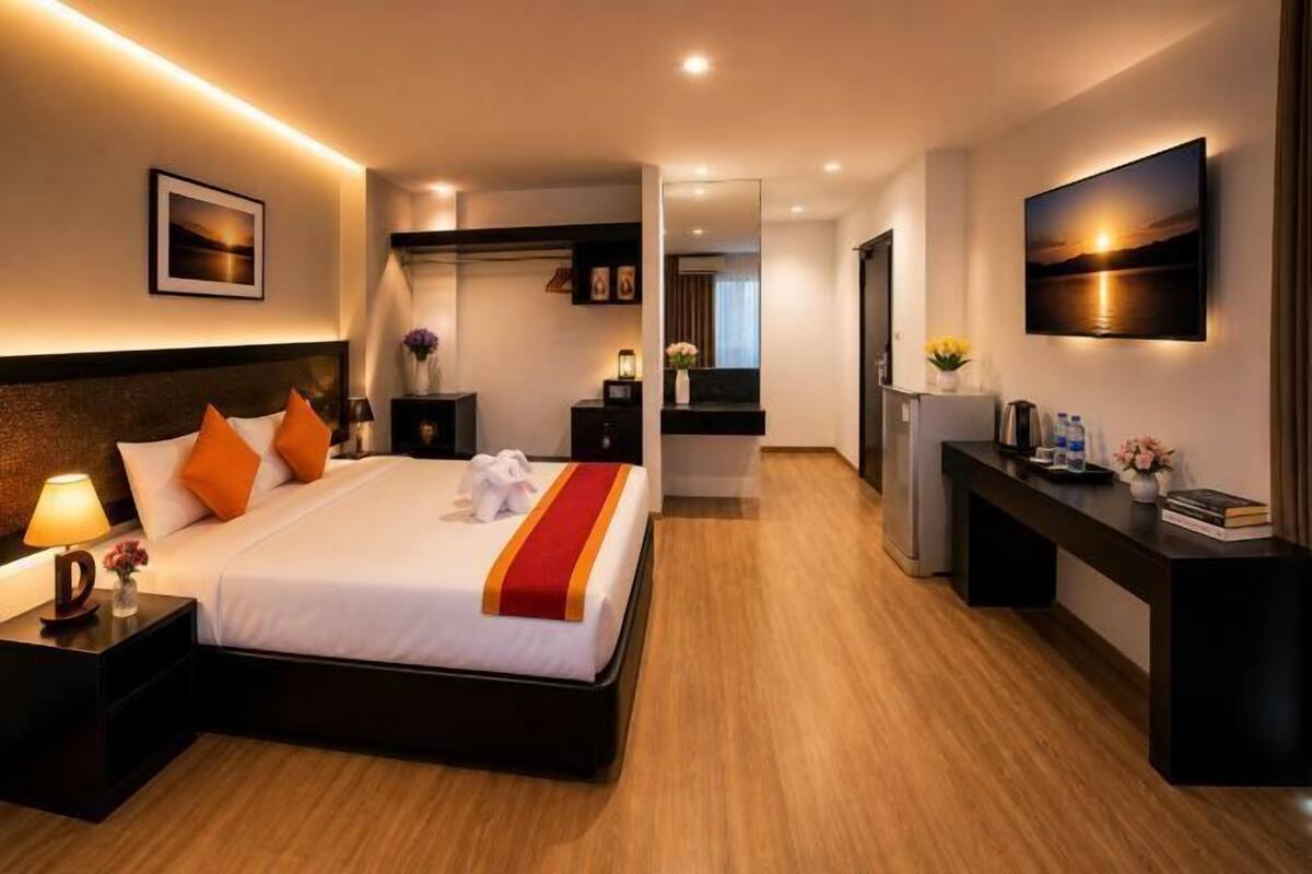 A hotel room with a large bed, bedside tables, a desk, a mirror, and a TV.