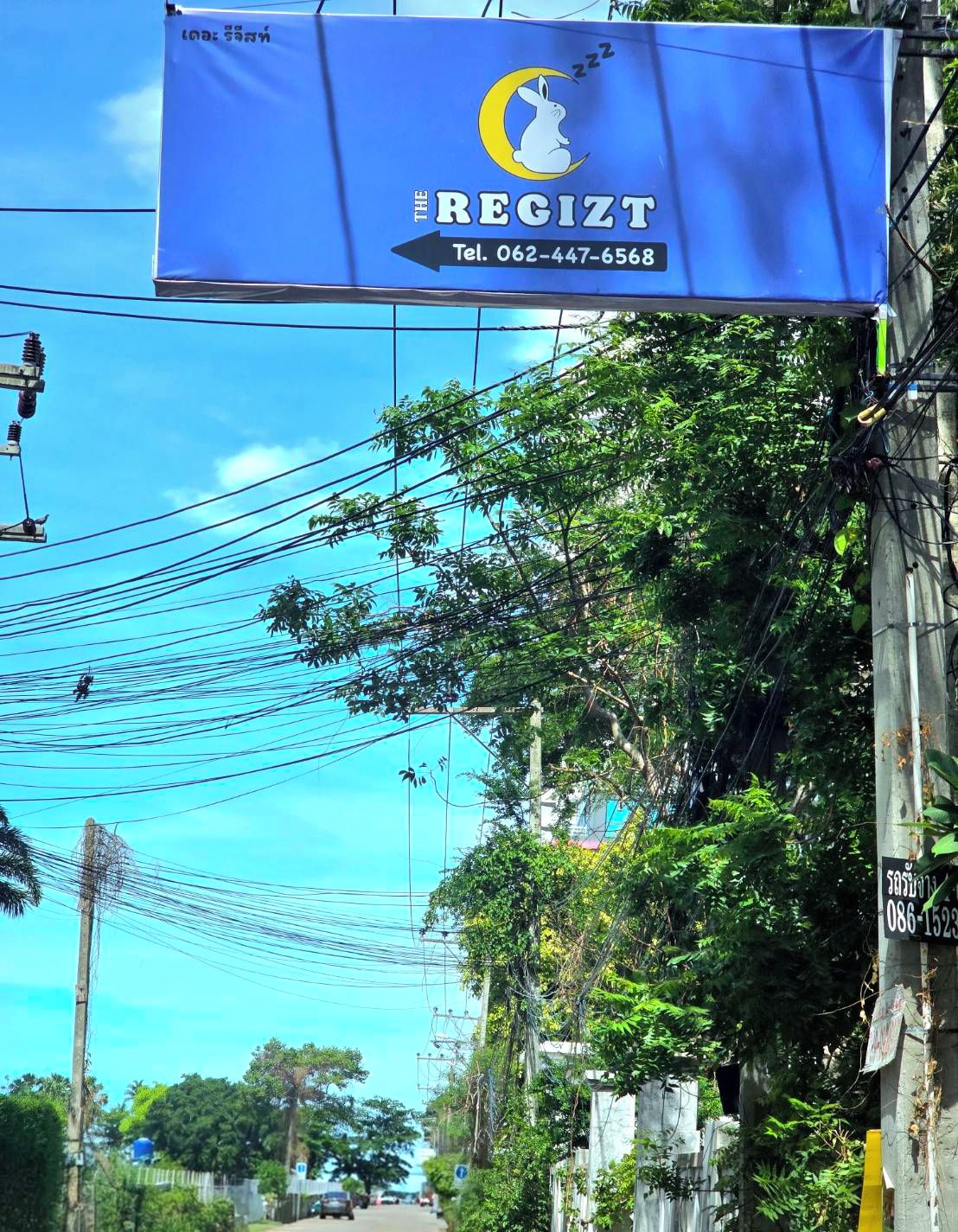 Una pancarta azul con el logotipo de un conejo y el texto "THE REGIT" y un número de teléfono.