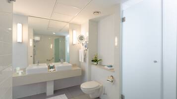 Un baño moderno con un espejo grande, dos lavamanos, inodoro y zona de ducha.
